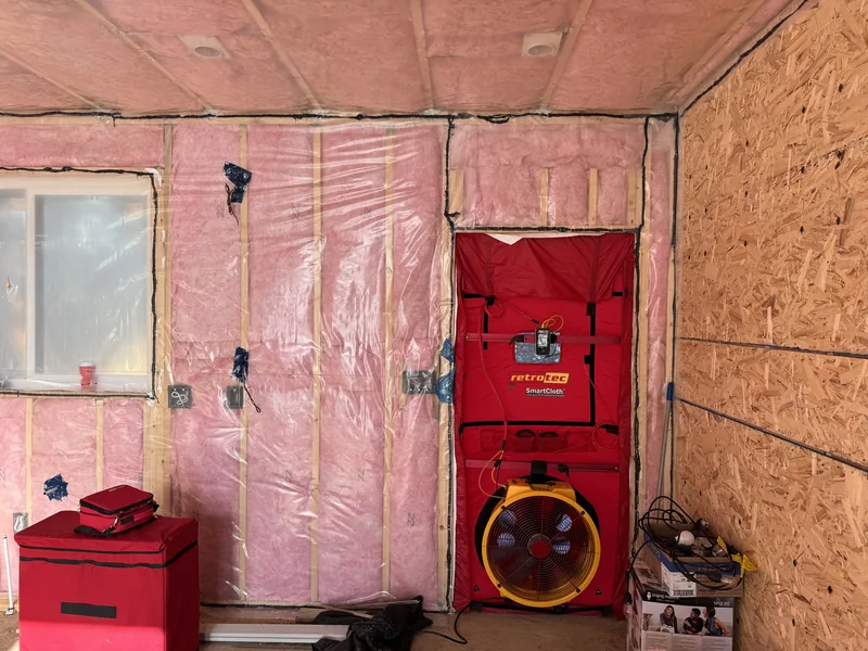 Mid-construction blower-door test setup in an insulated new home before drywall